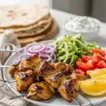 Greek chicken souvlaki with creamy tzatziki and fresh vegetables on a platter