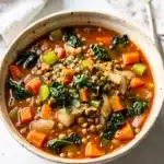 Hearty lentil vegetable soup recipe in a rustic bowl with fresh parsley garnish.