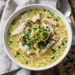 Creamy lemon chicken orzo soup in a rustic bowl with fresh parsley garnish.
