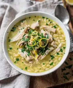 Creamy lemon chicken orzo soup in a rustic bowl with fresh parsley garnish.