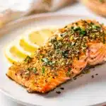 Lemon herb salmon with creamy sauce on a white plate close up