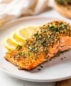 Lemon herb salmon with creamy sauce on a white plate close up