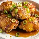 Slow cooker honey garlic chicken served with rice and green onions.