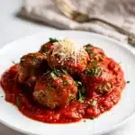 Slow Cooker Italian meatballs in tomato sauce over spaghetti with Parmesan.