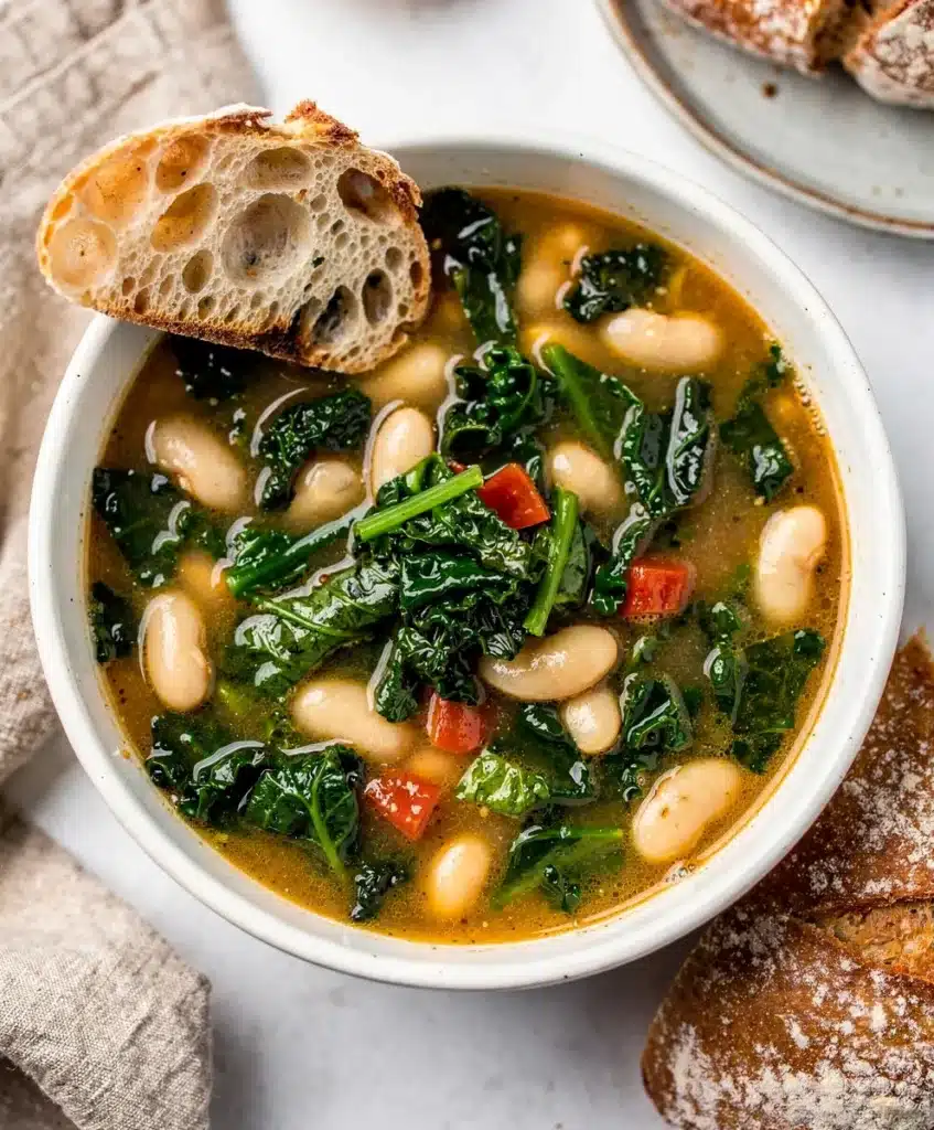 Creamy Tuscan white bean kale soup garnished with Parmesan and olive oil