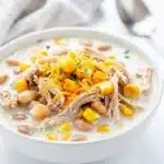 Creamy white chicken chili with beans and corn in a rustic ceramic bowl.