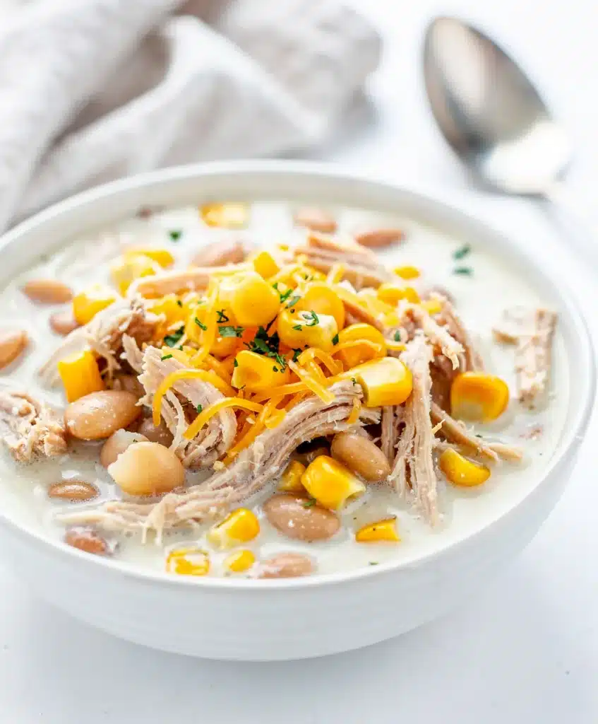 Creamy white chicken chili with beans and corn in a rustic ceramic bowl.