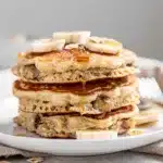 Fluffy banana oatmeal pancakes with maple syrup and walnuts on rustic table