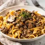 Creamy ground beef stroganoff with egg noodles and mushrooms on rustic plate