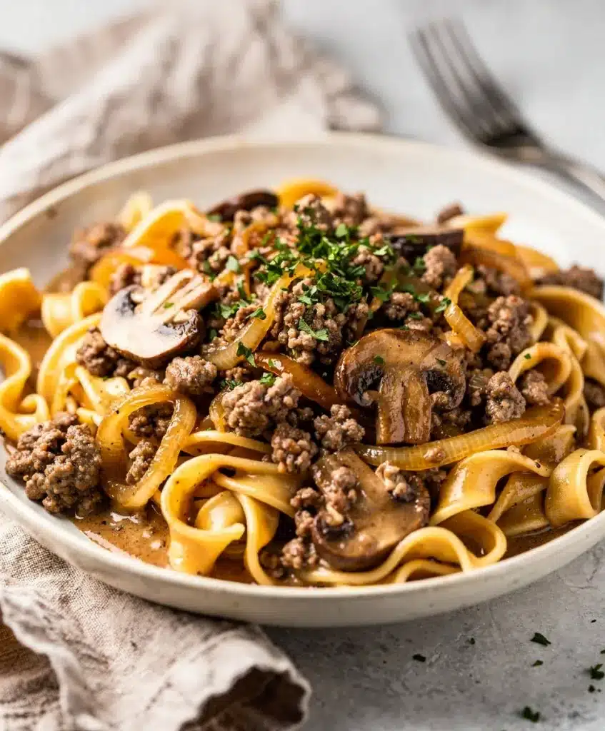 Creamy ground beef stroganoff with egg noodles and mushrooms on rustic plate