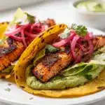 Blackened salmon tacos with avocado crema in a close up food photo