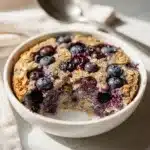 Blueberry baked oatmeal with crispy golden edges and creamy glossy surface.
