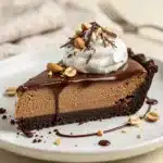 Decadent chocolate peanut butter pie slice with whipped cream and garnish