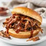 Crockpot BBQ pulled pork recipe with glossy saucy shredded meat close up