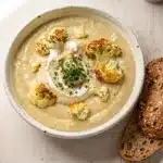 Creamy roasted garlic cauliflower soup in a rustic bowl with fresh parsley garnish