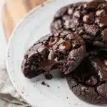 Fudgy brownie cookies with cracked tops and melty chocolate chips on wood.