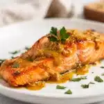 Maple Dijon salmon with sticky glaze and dill on a rustic wooden board.