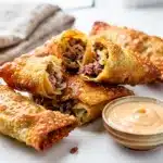 Crispy mini Reuben egg rolls with corned beef and sauerkraut for dipping.