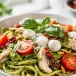 Creamy pesto chicken pasta salad with tomatoes, mozzarella, and toasted pine nuts.