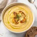 Creamy roasted garlic cauliflower soup in a rustic bowl with thyme.