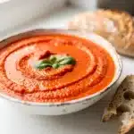 Creamy roasted red pepper soup with coconut milk and fresh basil garnish