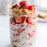 Strawberry cheesecake overnight oats in a jar with fresh fruit topping.