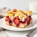 Golden brown strawberry dump cake with red filling on rustic ceramic dish