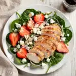 Fresh strawberry spinach salad with chicken feta and almonds on wood