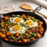 Crispy sweet potato breakfast hash with sunny side up eggs close up