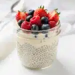 Creamy vanilla chia pudding topped with fresh mixed berries in a glass jar.