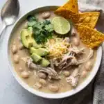 Creamy white chicken chili with shredded chicken beans and avocado garnish