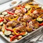 Colorful roasted chicken and veggies on a white sheet pan for easy dinners.