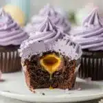 Chocolate Cadbury egg cupcake sliced open reveals molten creme egg center.