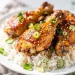 Crockpot honey garlic chicken with glossy sticky sauce and green onion garnish.