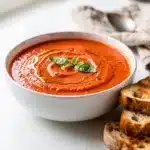 Creamy tomato basil soup with fresh herbs in a rustic bowl