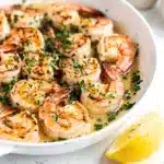 Succulent garlic butter shrimp in a rustic pan with lemon and parsley.
