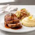 Herb roasted pork tenderloin sliced on a rustic wooden cutting board.