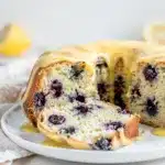 Moist lemon blueberry pound cake slice with glossy glaze on white plate