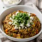 Slow cooker Mediterranean lentils with kale and feta in a rustic ceramic bowl.