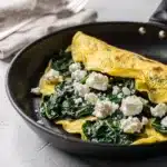 Spinach feta omelet recipe with creamy eggs and melted cheese close up