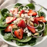 Fresh strawberry spinach salad with feta cheese and toasted almonds in a bowl