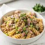 Creamy tuna pasta salad with peas and rotini in a homemade close-up.