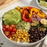 Colorful veggie loaded burrito bowl with rice, beans, salsa, and fresh avocado.