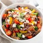 Colorful whole wheat veggie pasta salad with creamy feta and glossy vinaigrette dressing.