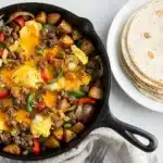Hearty breakfast burrito skillet with sausage, eggs, potatoes, and melted cheese.