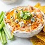 Buffalo chicken dip with melted cheese served with celery and chips