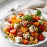 Colorful Caprese pasta salad with fresh tomatoes and creamy mozzarella cheese.