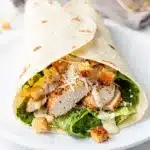 Sliced chicken Caesar wrap reveals tender chicken crisp lettuce and creamy dressing