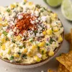Creamy Mexican street corn dip with cotija cheese and chili powder in bowl