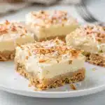 Homemade coconut cream pie bar with creamy filling and toasted coconut topping.